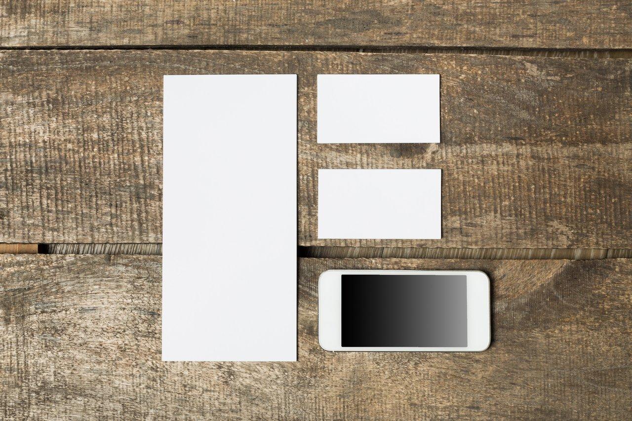 Matériel d'impression pour le marketing local : flyers, brochures et plaquettes sur une table en bois.