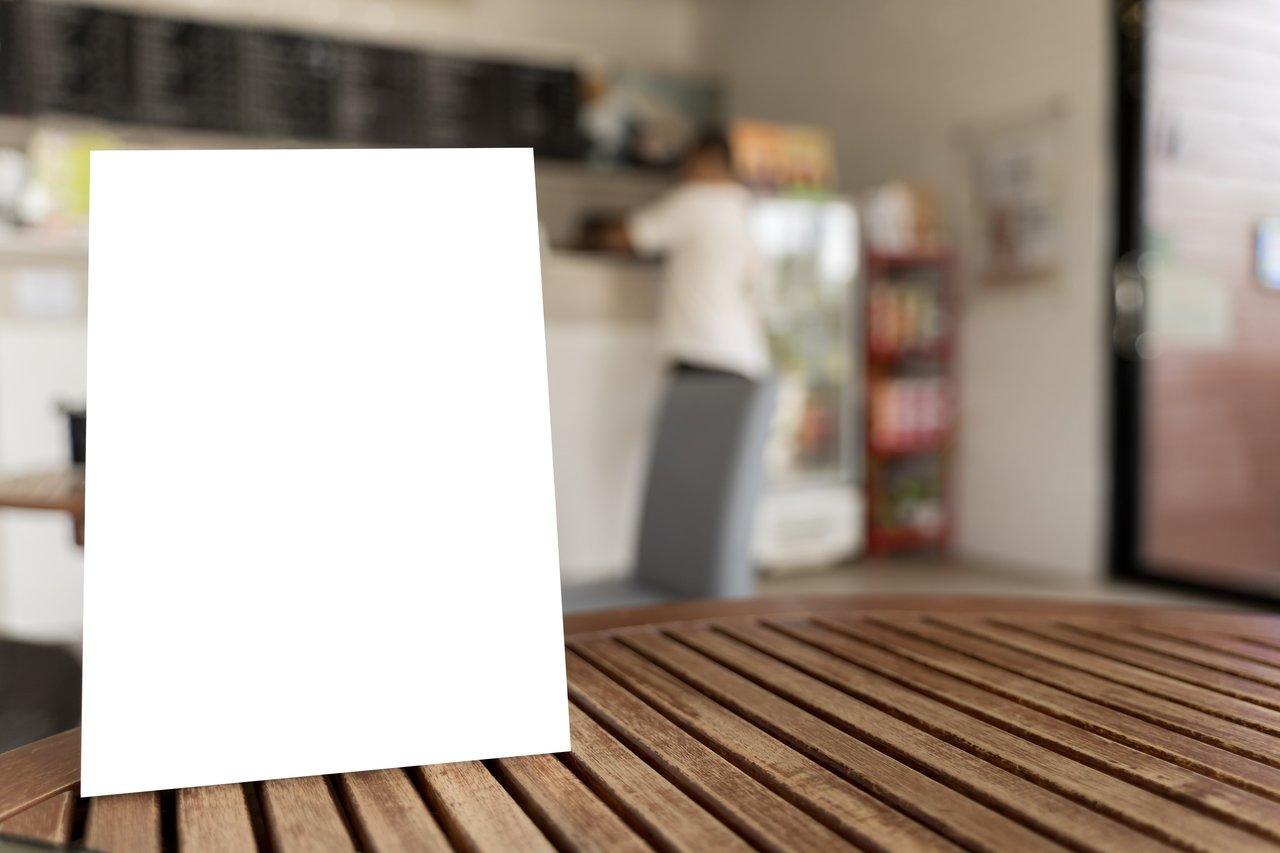 Menus restaurant avec finition glossy ou matte, élégants et résistants, posés sur table en bois dans une ambiance lumineuse sophistiquée.