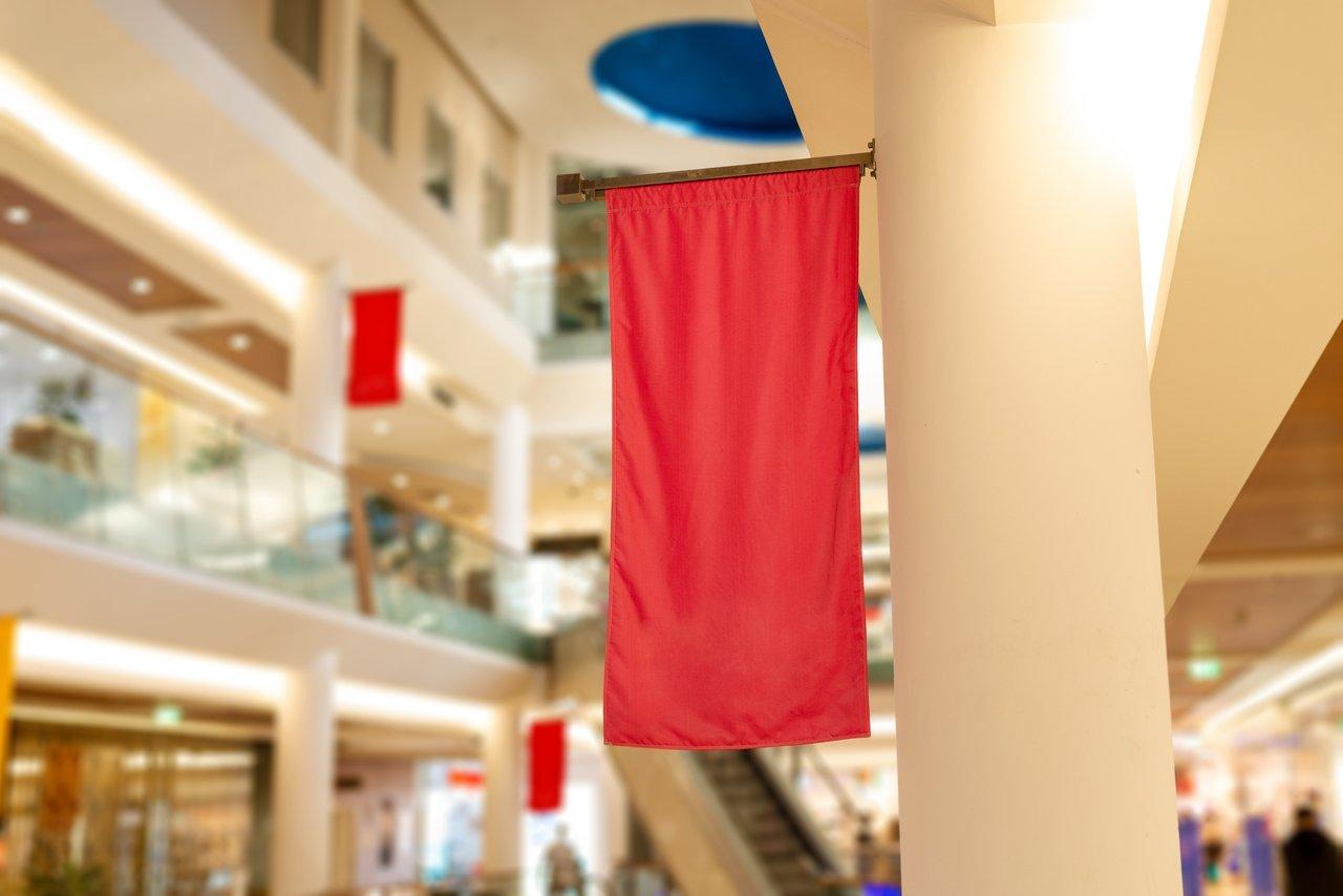 Un hanging retail banner rouge suspendu en tête de gondole, idéal pour promouvoir produits et logos.