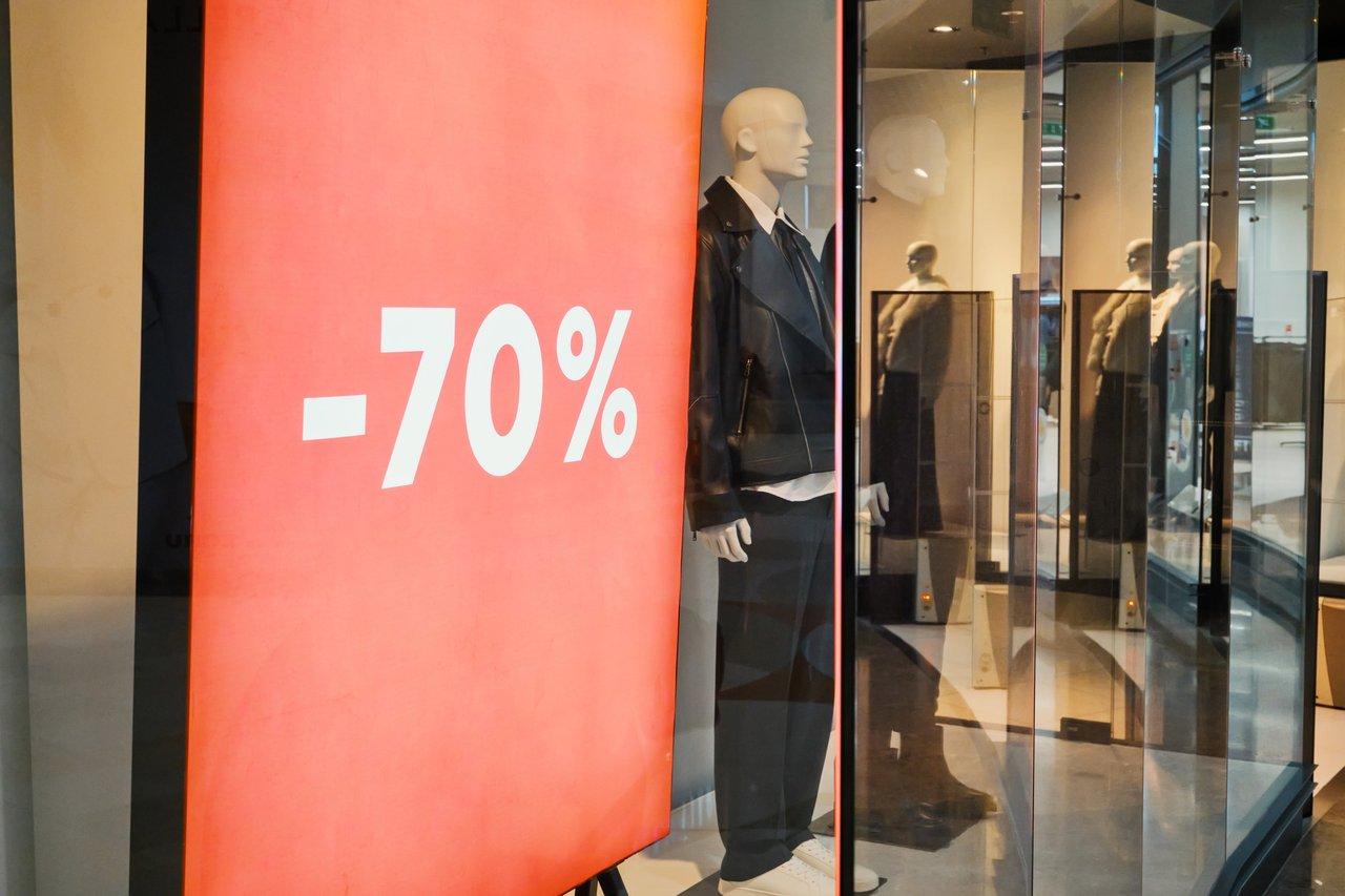 Vitrine de prêt-à-porter avec affichage de soldes, mannequins et matériaux pour une vitrine commerciale attrayante.